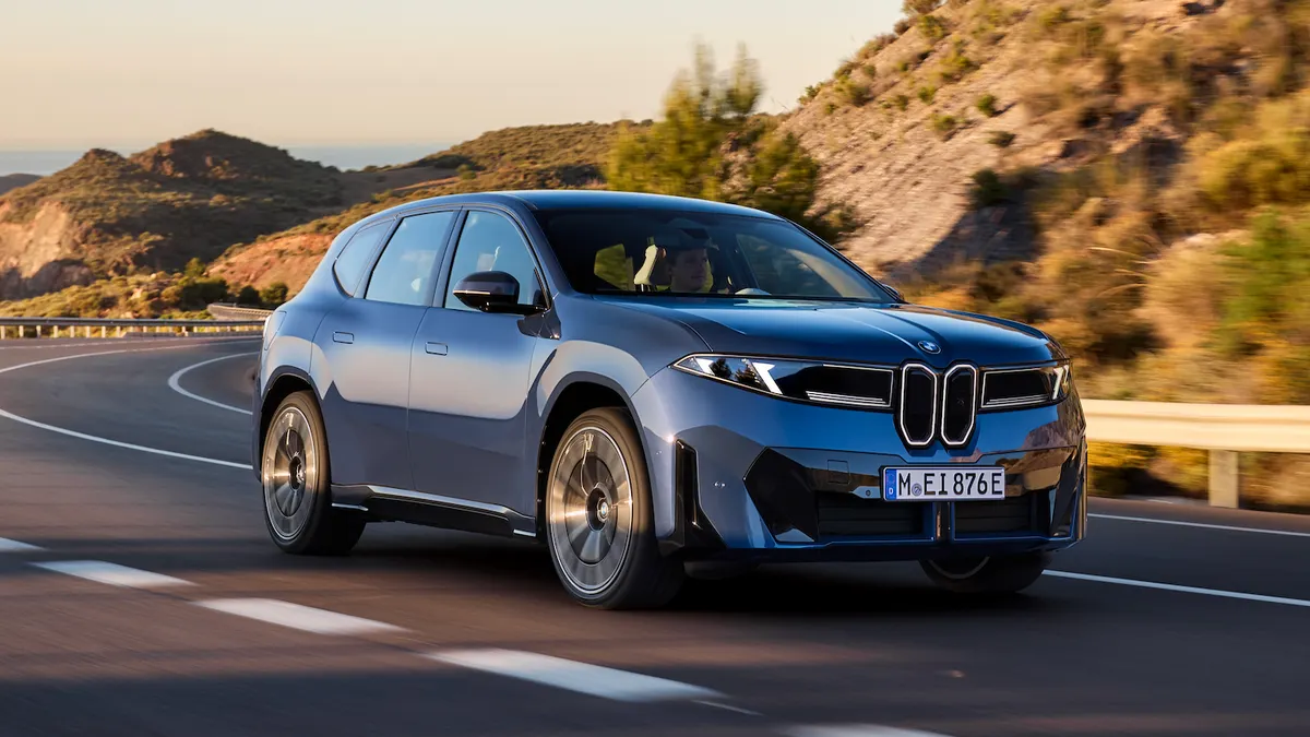 A blue BMW iX3 electric SUV driving on a highway