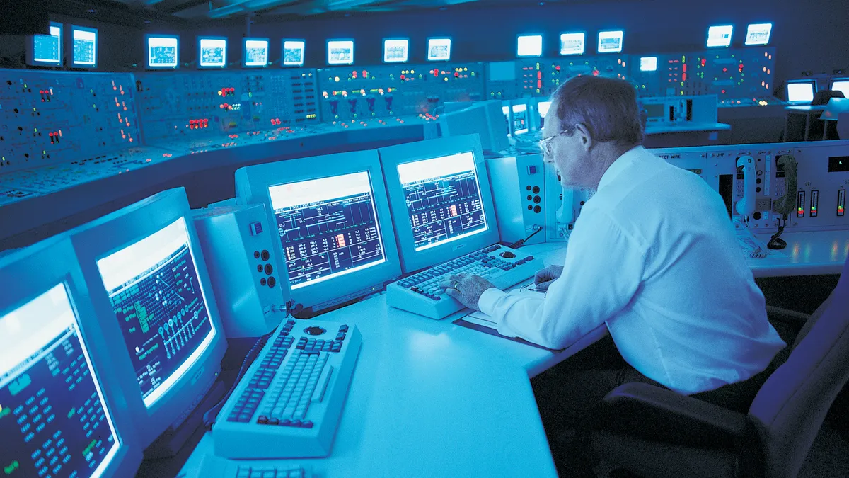 Engineer sitting at a control panel in a nuclear power station.