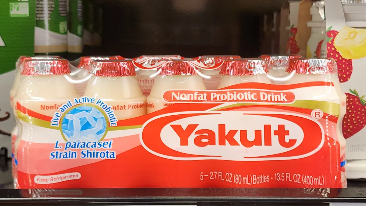 A pack of Yakult on a shelf in a fridge wrapped in plastic.