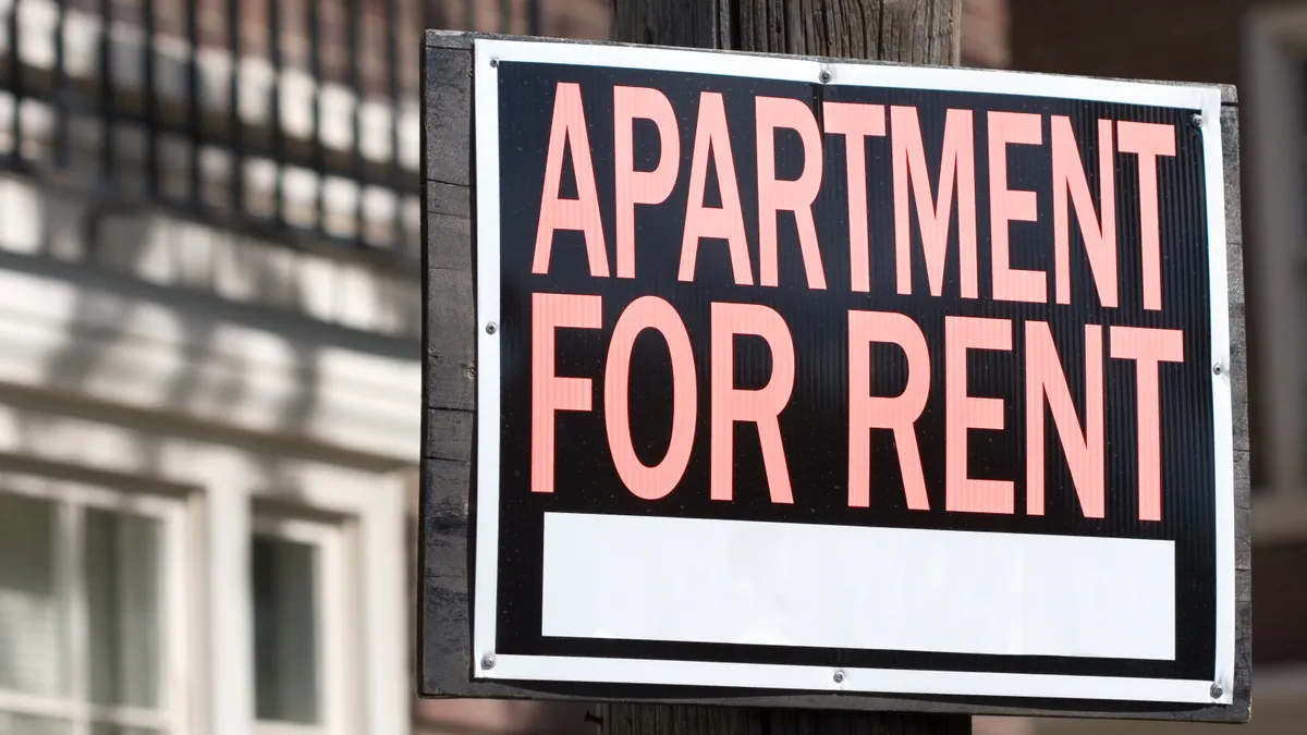 A sign on a wooden post reading "APARTMENT FOR RENT."