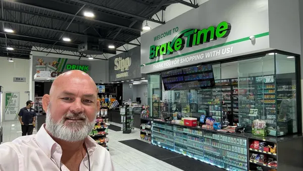 A photo of a person standing inside a convenience store. A sign on the wall says "Welcome to BrakeTime. Thank you for shopping with us!"