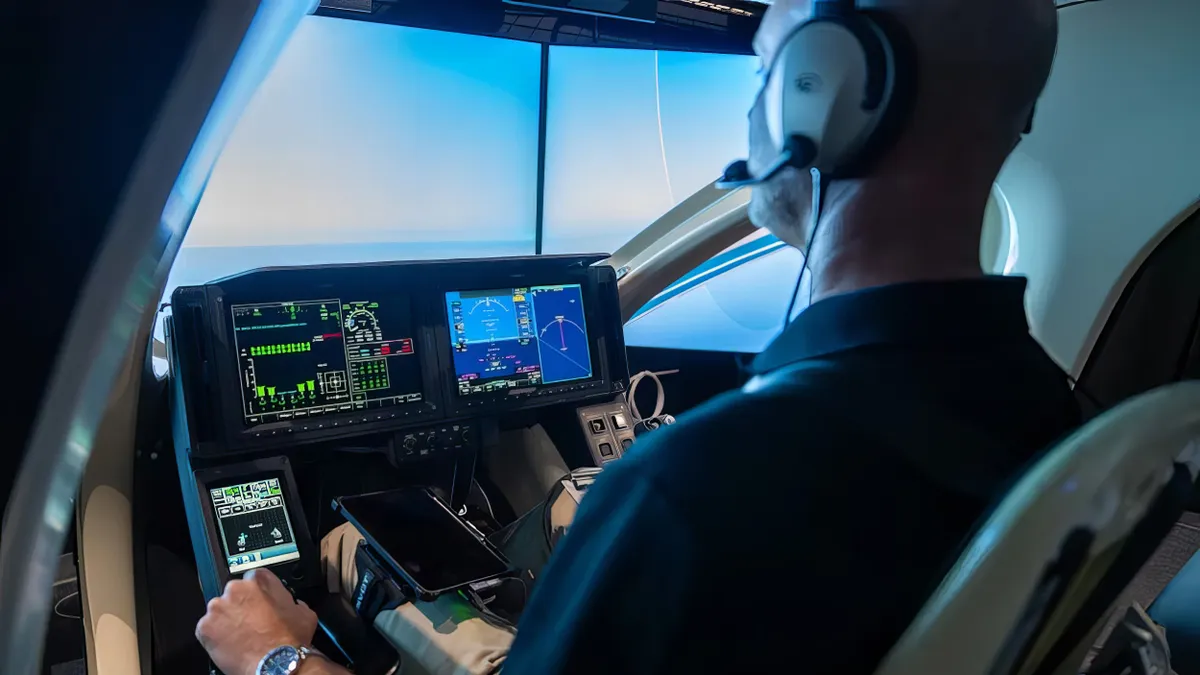 View into the cockpit of an air taxi flight simulator with a man at the controls.