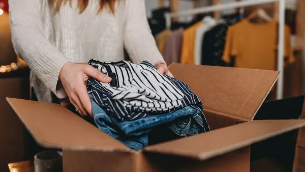 A person puts clothing inside a cardboard box.
