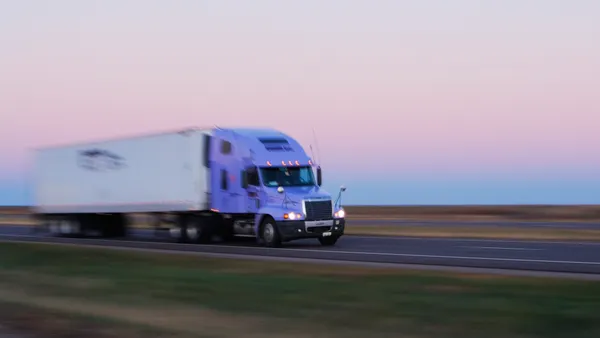 A blurred photo showing motion of a tractor hauling a PRIME Inc. trailer.