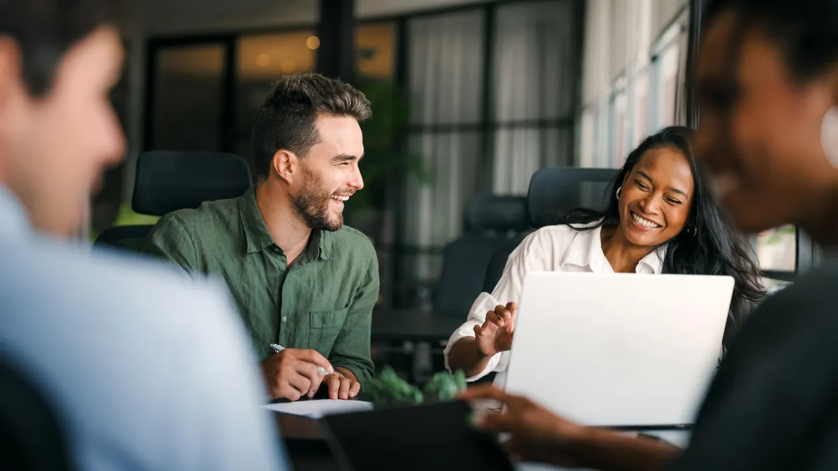 A group of colleagues collaborating around a table in a bright modern office.