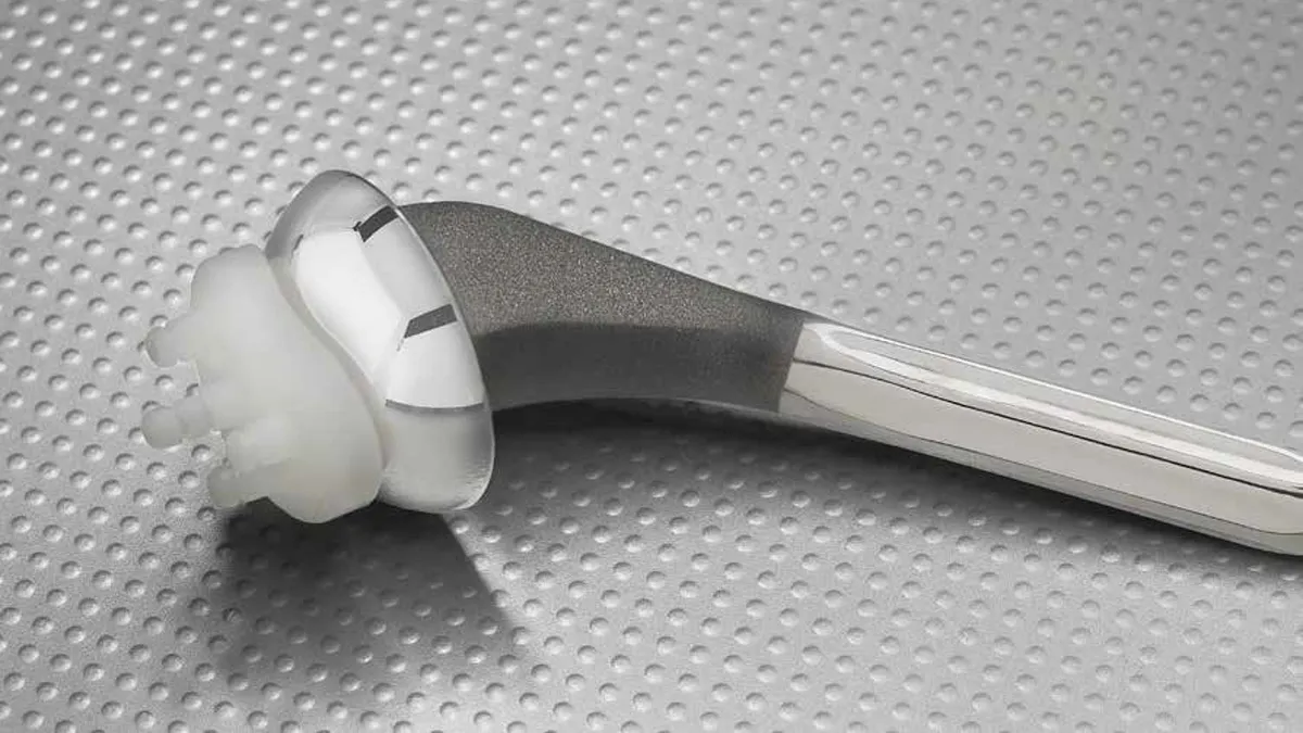 A metal shoulder implant with a rounded, plastic socket.