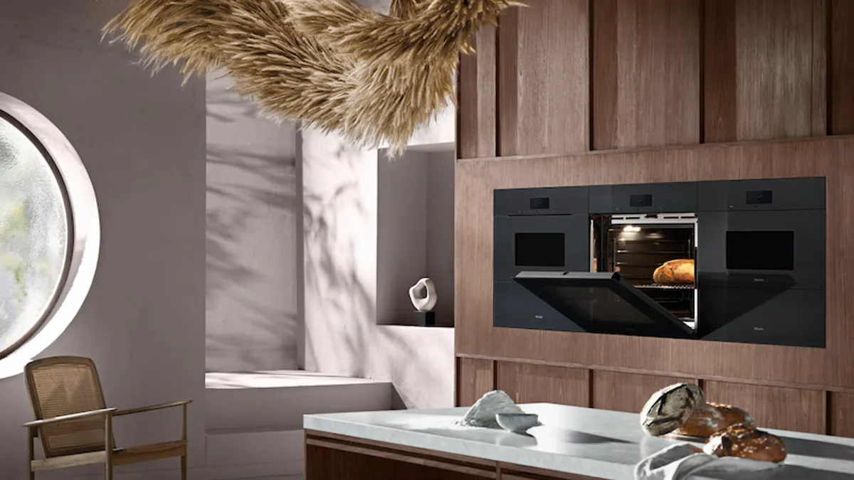 A loaf of bread in a black oven with its door opening in the kitchen.