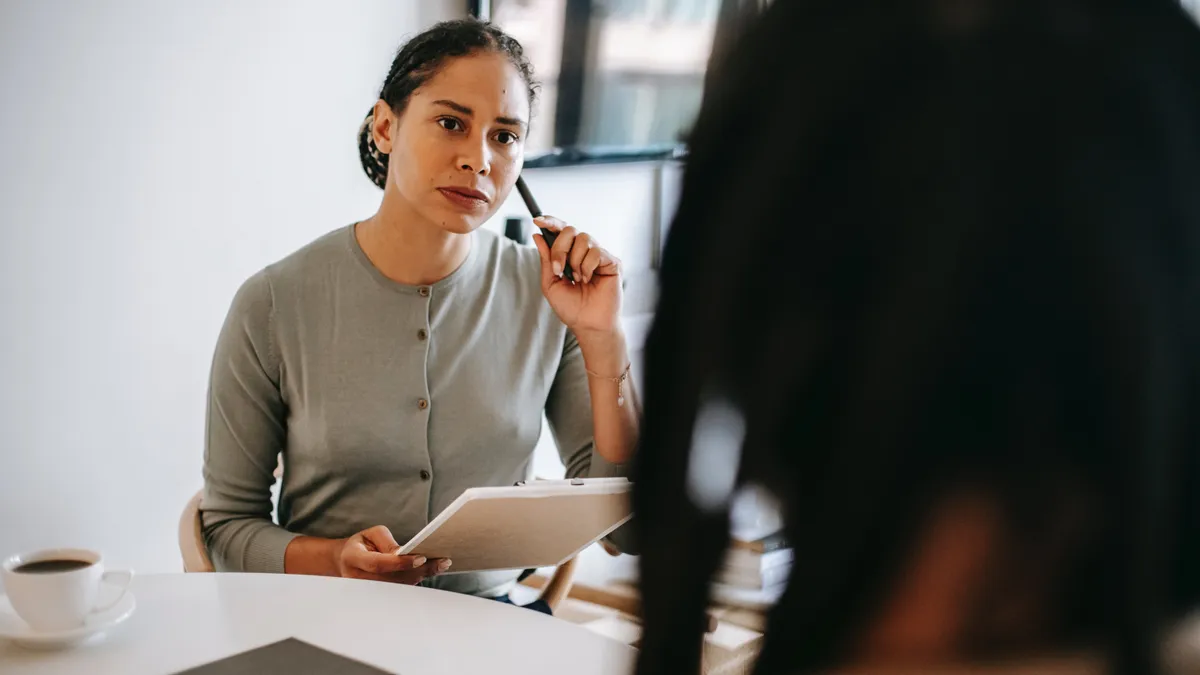 Serious woman of color is listening to her peer