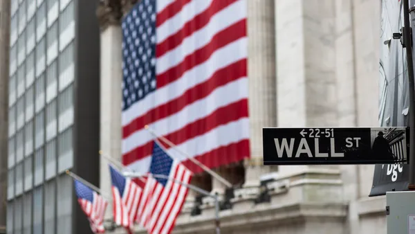 Flags fly at full staff outside the NYSE with the Wall ST sign in the foreground