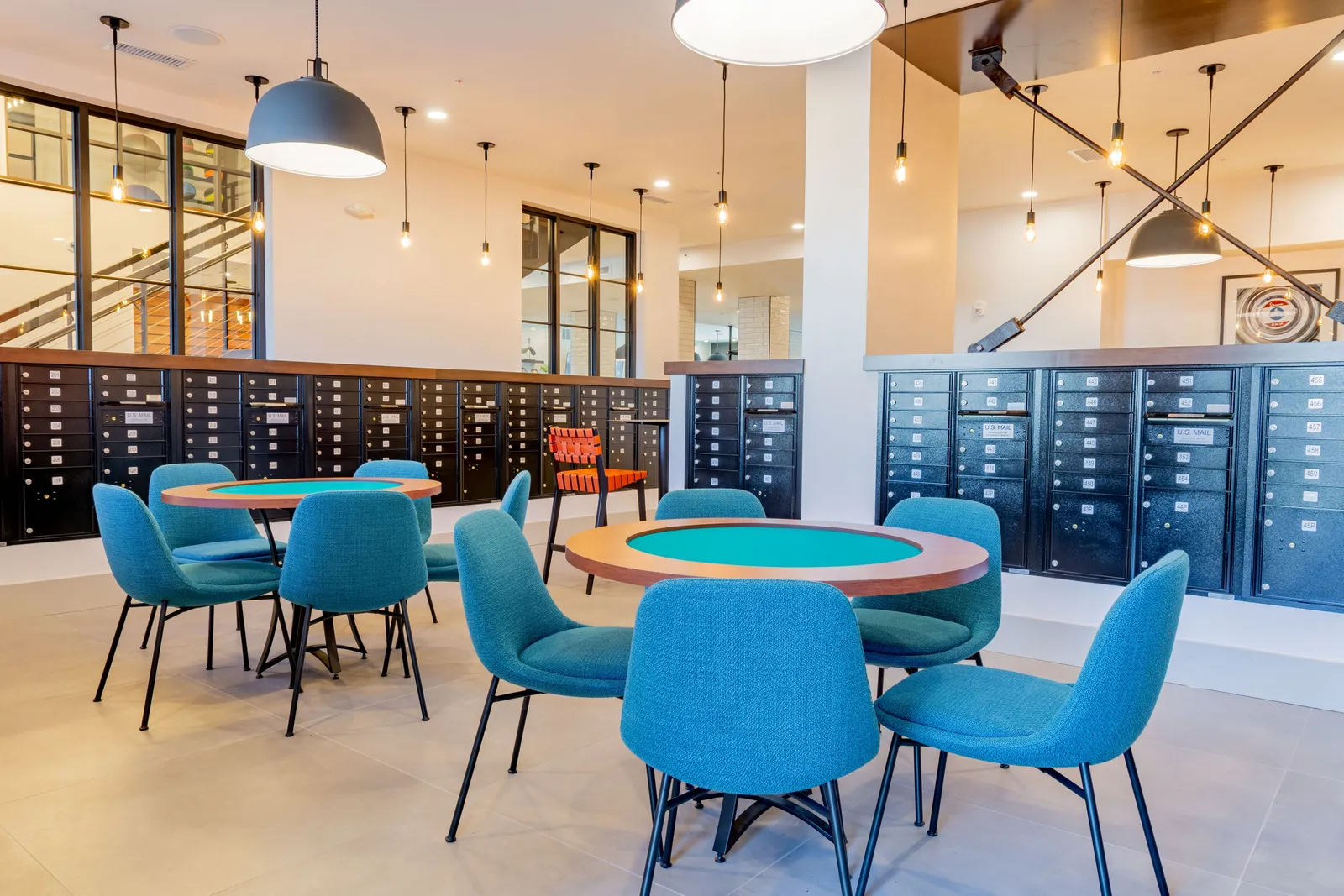 A room with tables and chairs surrounded by a wall of mailboxes.