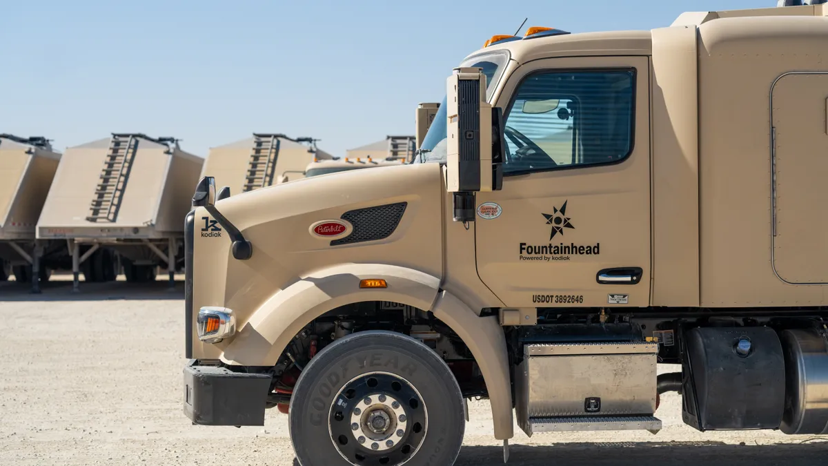 An Atlas Energy Solutions autonomous truck without a driver in the Permian Basin next to other vehicles.