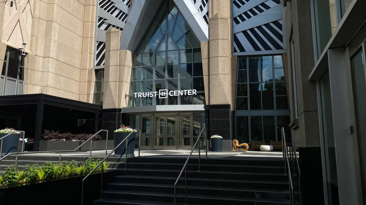 A stone and glass building entrance is shown with the words "Truist Center" above the doorway, and stairs in the foreground.