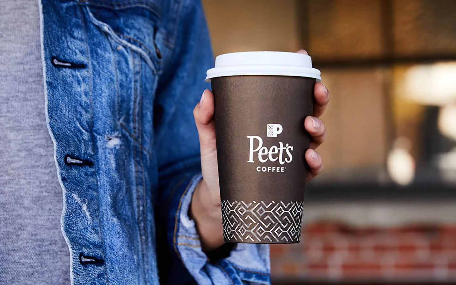 An image of a hand holding a Peet's Coffee cup