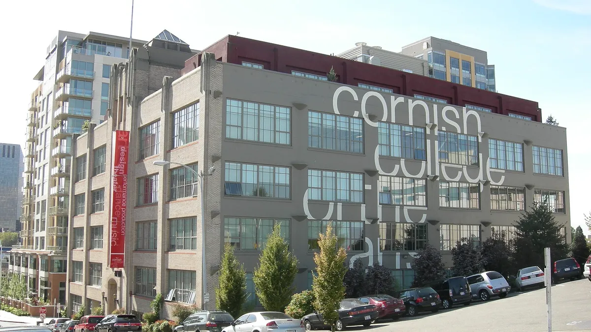 Large sign for the college broken by windows across multistory building in city environment.