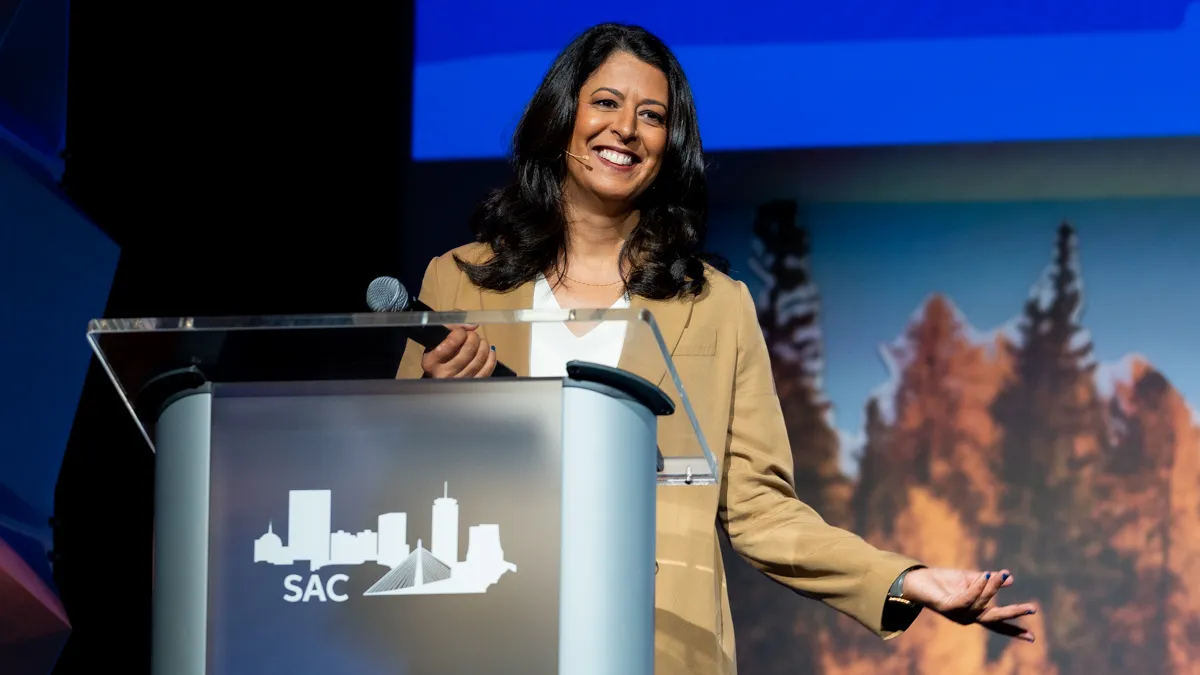 Amina Razvi speaks at a podium on a stage.