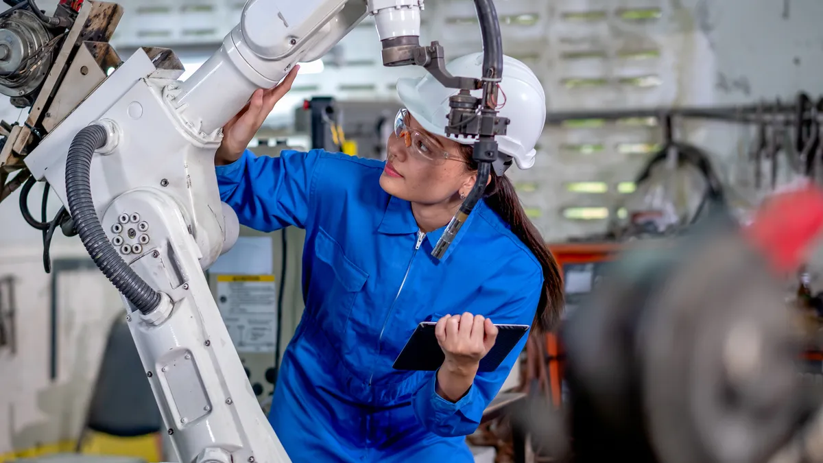 A factory employee works on a robotic machine.