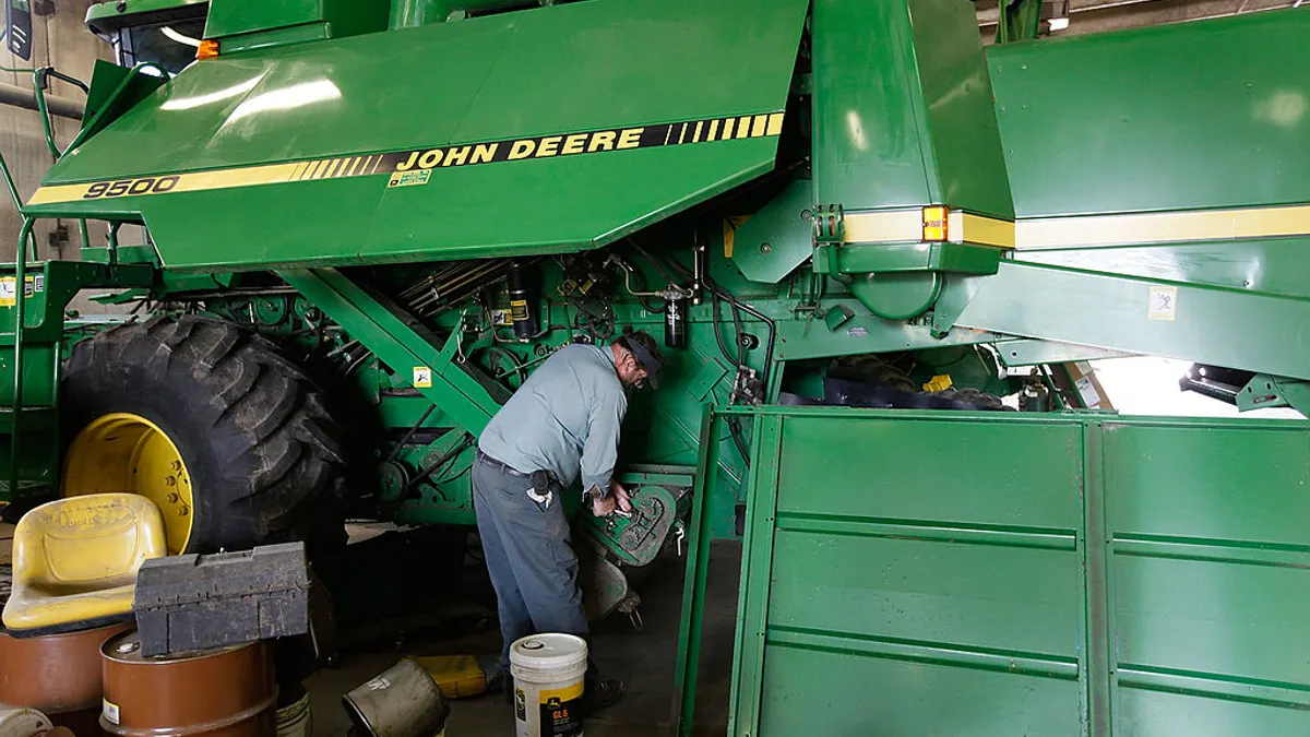 A man works on a giant green combine