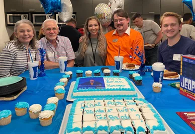 Pilot Flying J guest services agent Brian Henegar poses for a photo with family members and his manager in front of "Jeopardy!"-themed cakes at an office party for him Friday.