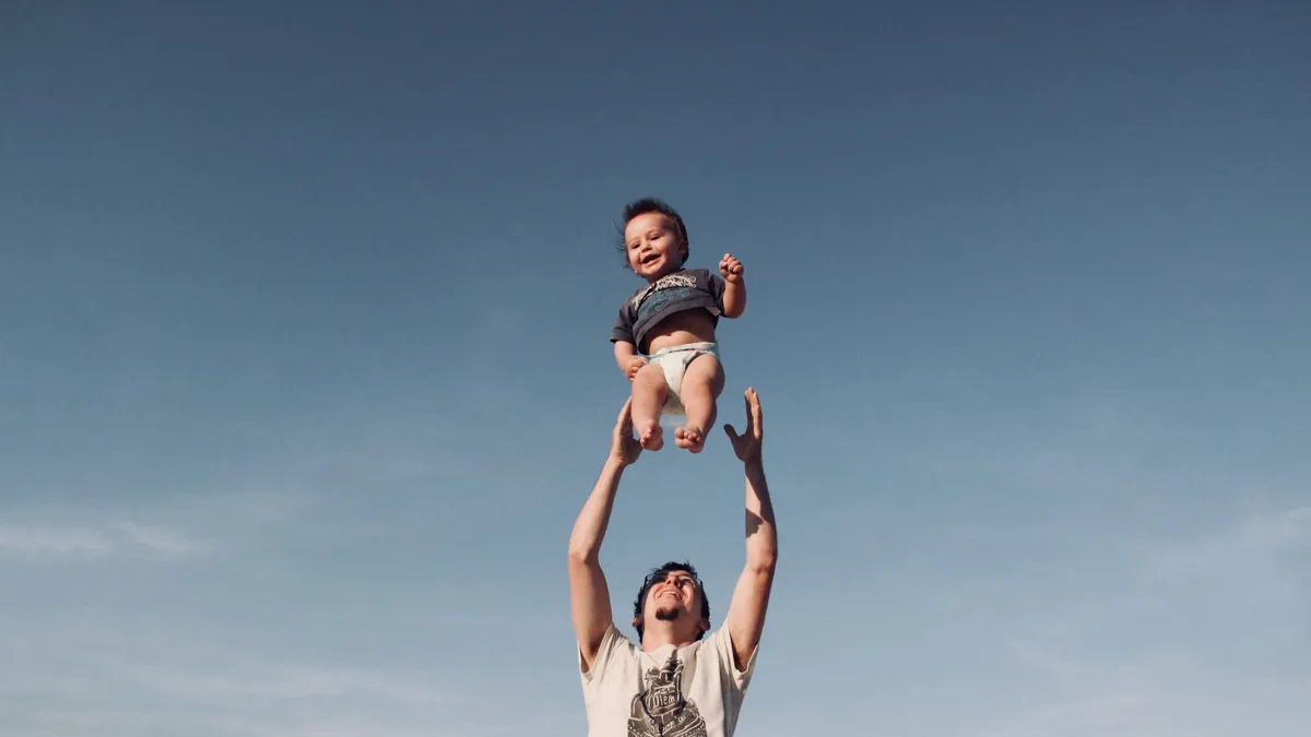 A father throws a baby in the air