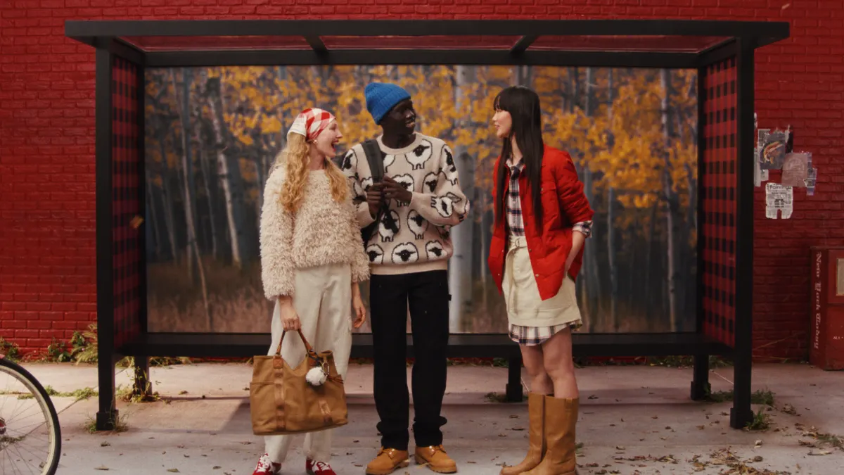 A group of people stand outside a bus stop in Woolrich x Target gear
