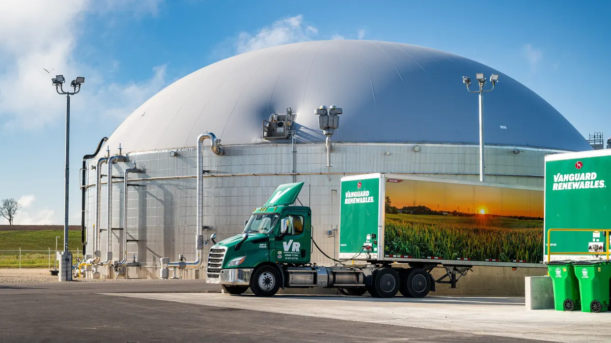A large domed facility with semi-trailers with "Vanguard Renewables" branding parked in front.