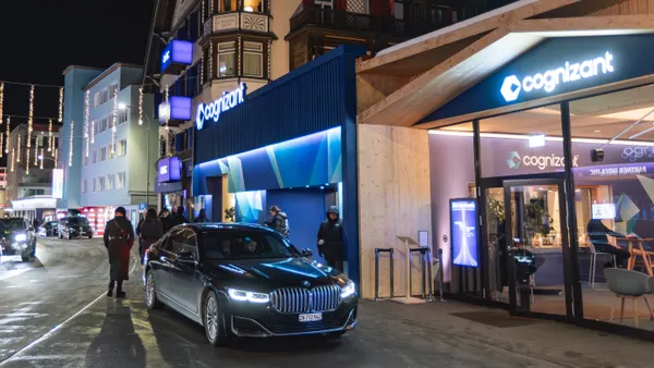Street view of a pedestrian and a vehicle outside a Cognizant branded pavilion at night in Davos, Switzerland, on January 21, 2026.