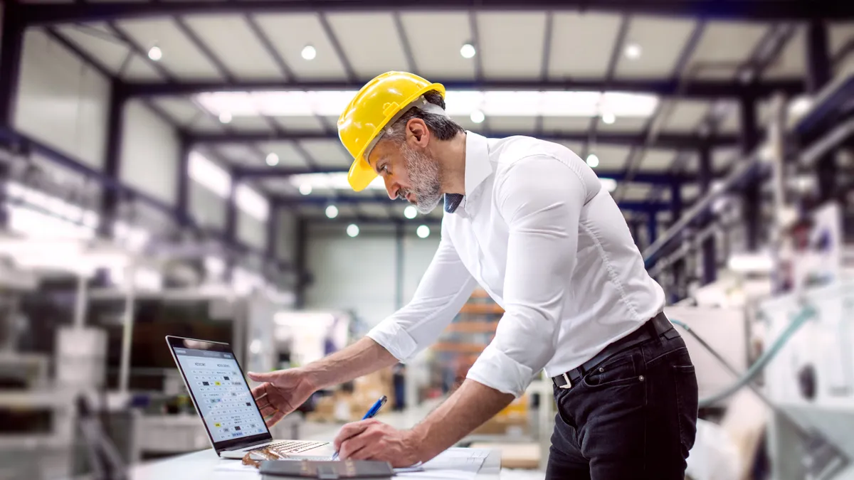 An industrial man engineer working with laptop in a factory