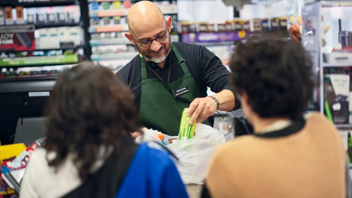 A cashier rings up two customers.