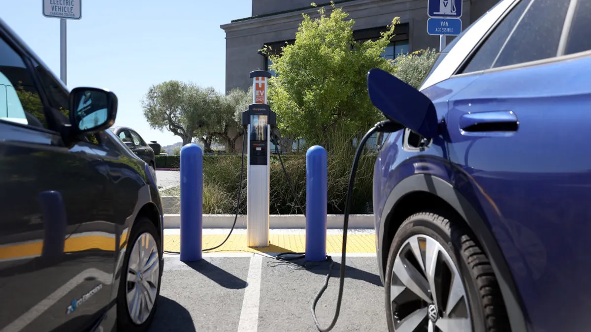 Two electric vehicles sit at an EV charging station.