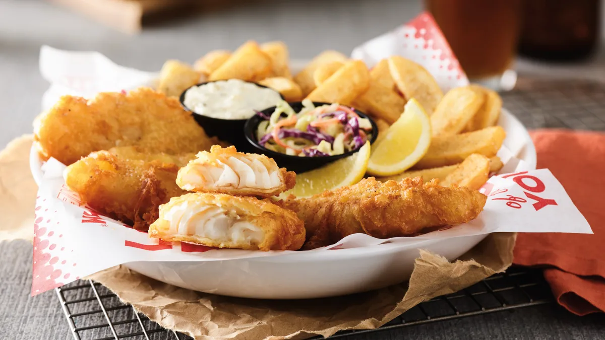 Battered fish and fries on a white plate.