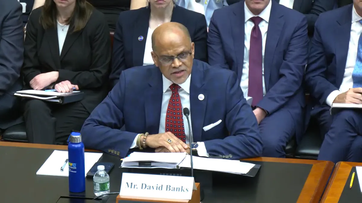 NYC Public Schools Chancellor David Banks sits in a House subcommittee hearing and speaks into a microphone