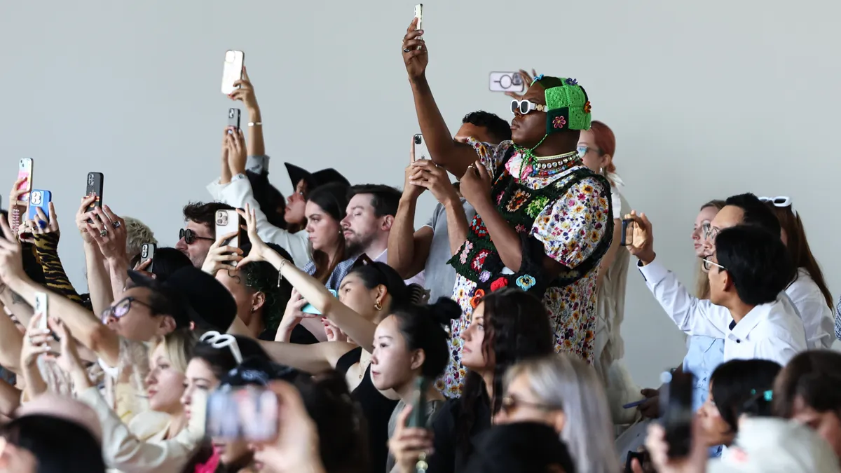 A crowd of spectators raise their cell phones to record the events taking place at the Concept Korea fashion show during New York Fashion Week.