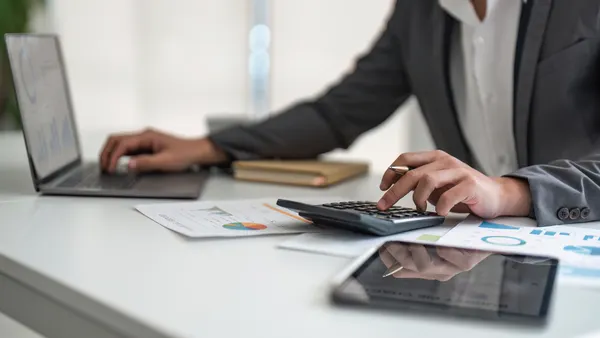 Person working at desk with laptop and calculator.