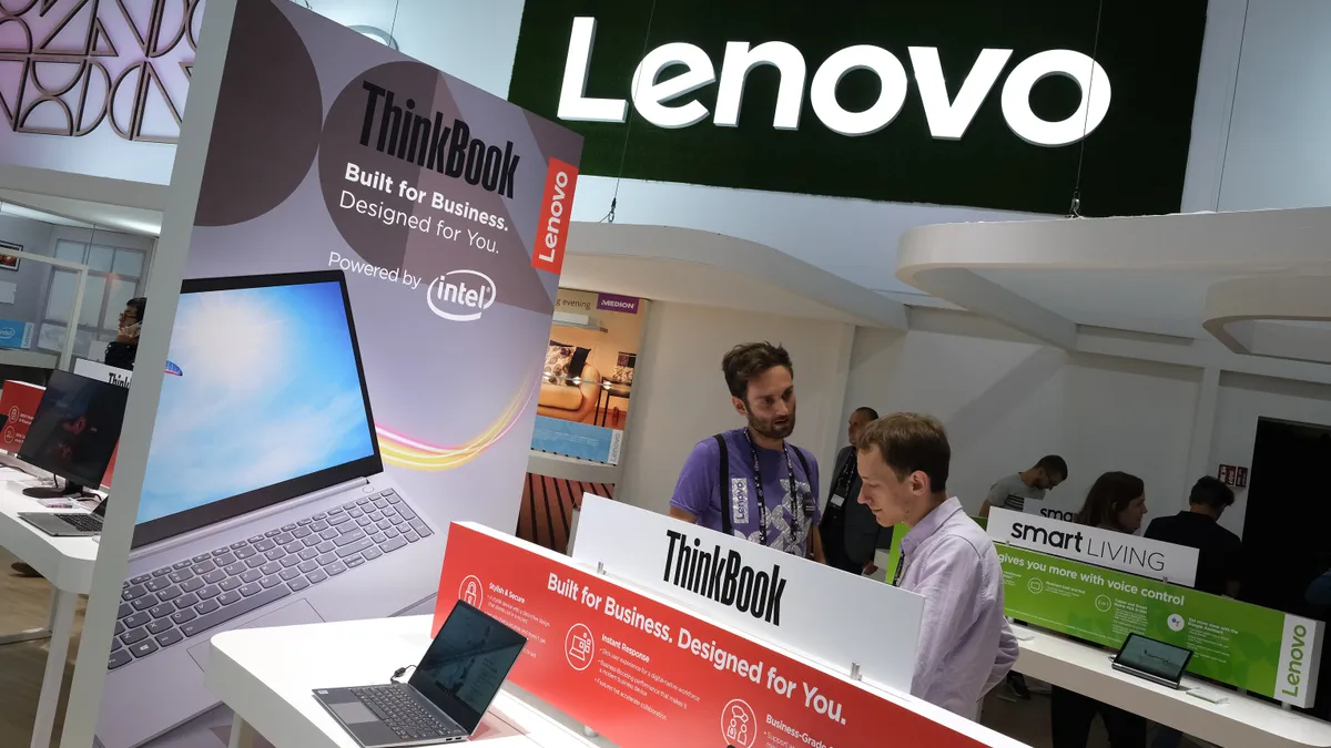 People looking at Lenovo ThinkBook products on display at a trade show.