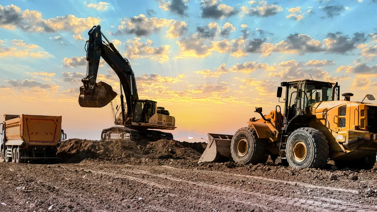 Excavators working on construction site at sunset.