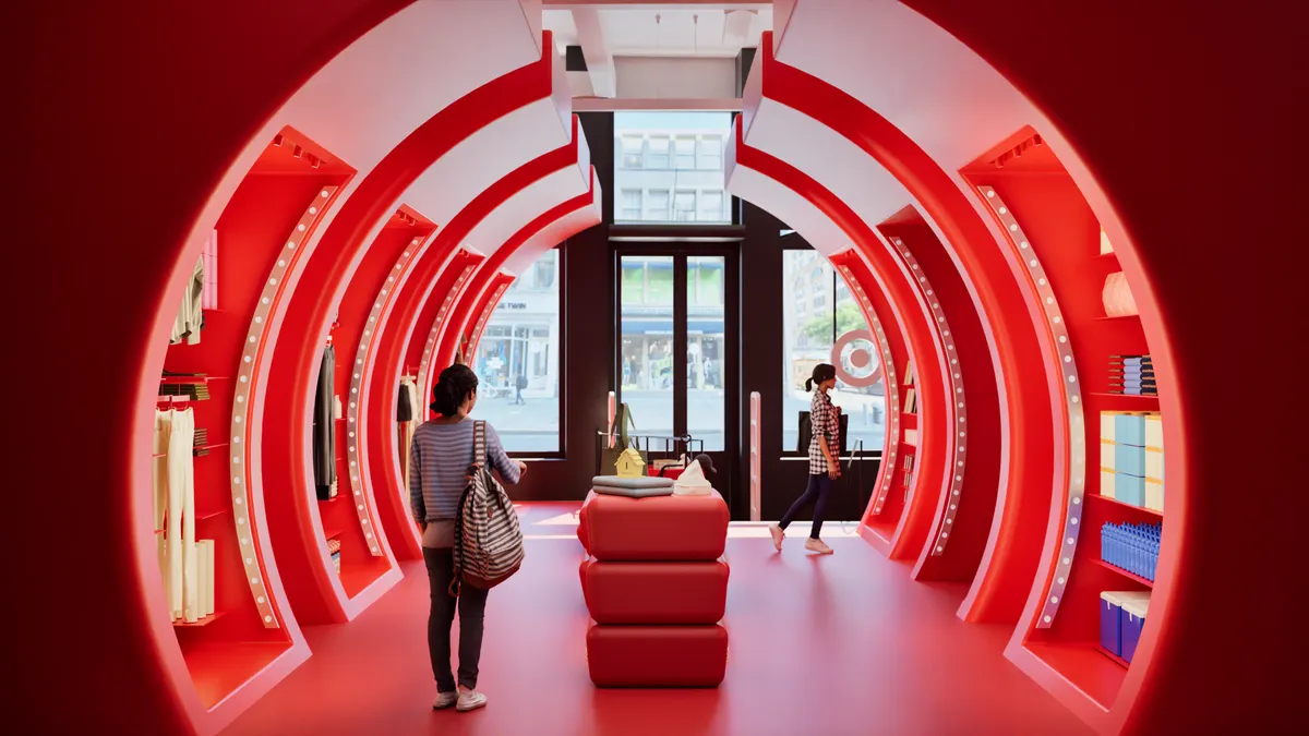 People walk through a red tunnel in a store.
