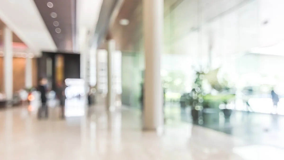 Blurred image of a hotel lobby with an interior view toward the reception hall and glass wall window