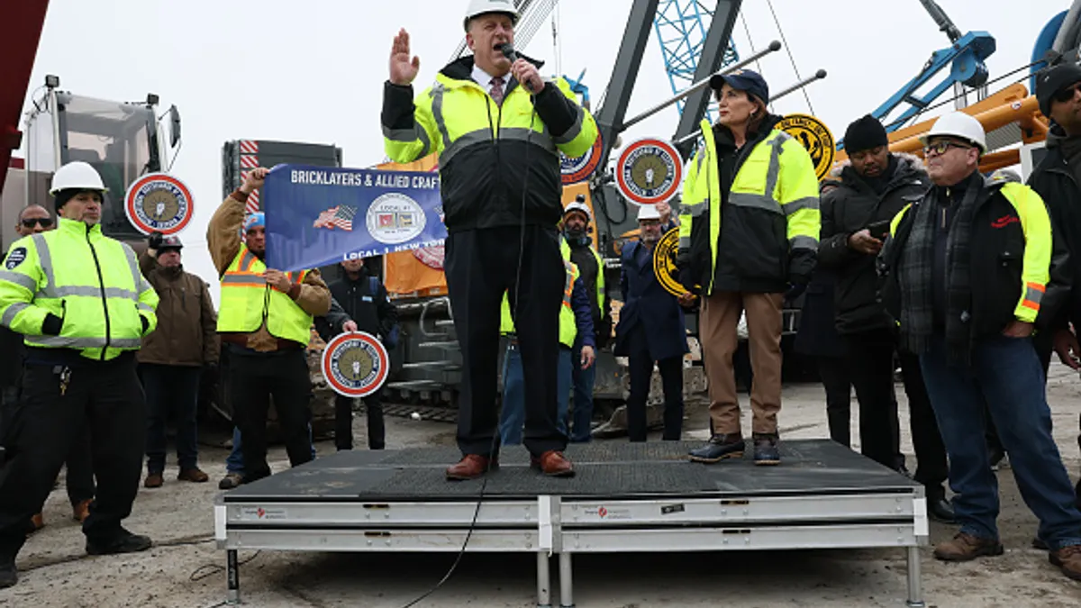 A group of people in construction gear stand at a speaking engagement.