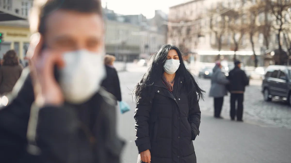 a man and a woman on the street wearing facemasks