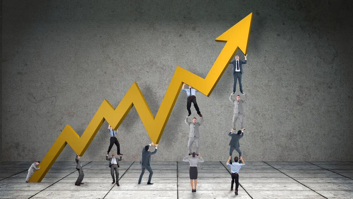 Business team holding up arrow against grey room