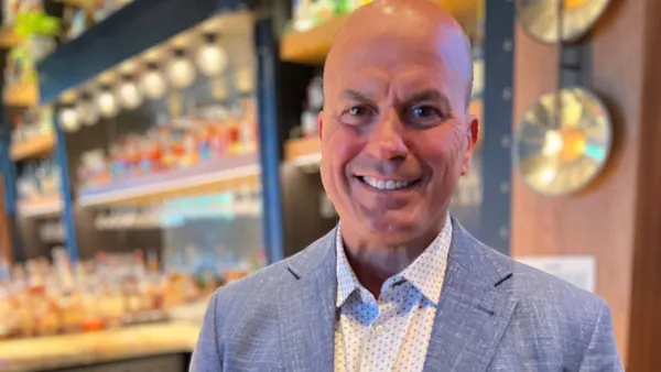 An image of a person smiling and wearing a gray suit.