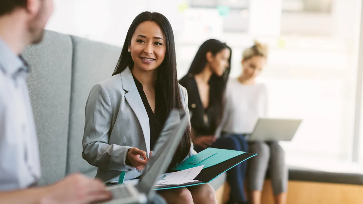 Multiracial young woman sits to discuss with work colleagues plans and ideas in modern coworking shared business office