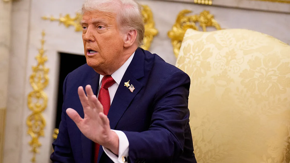 U.S. President Donald Trump raises his left hand while speaking during a meeting in the Oval Office at the White House.