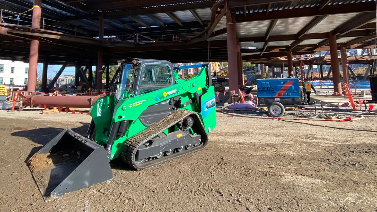 A green electric skid steer machine from Bobcat sits on a construction site.