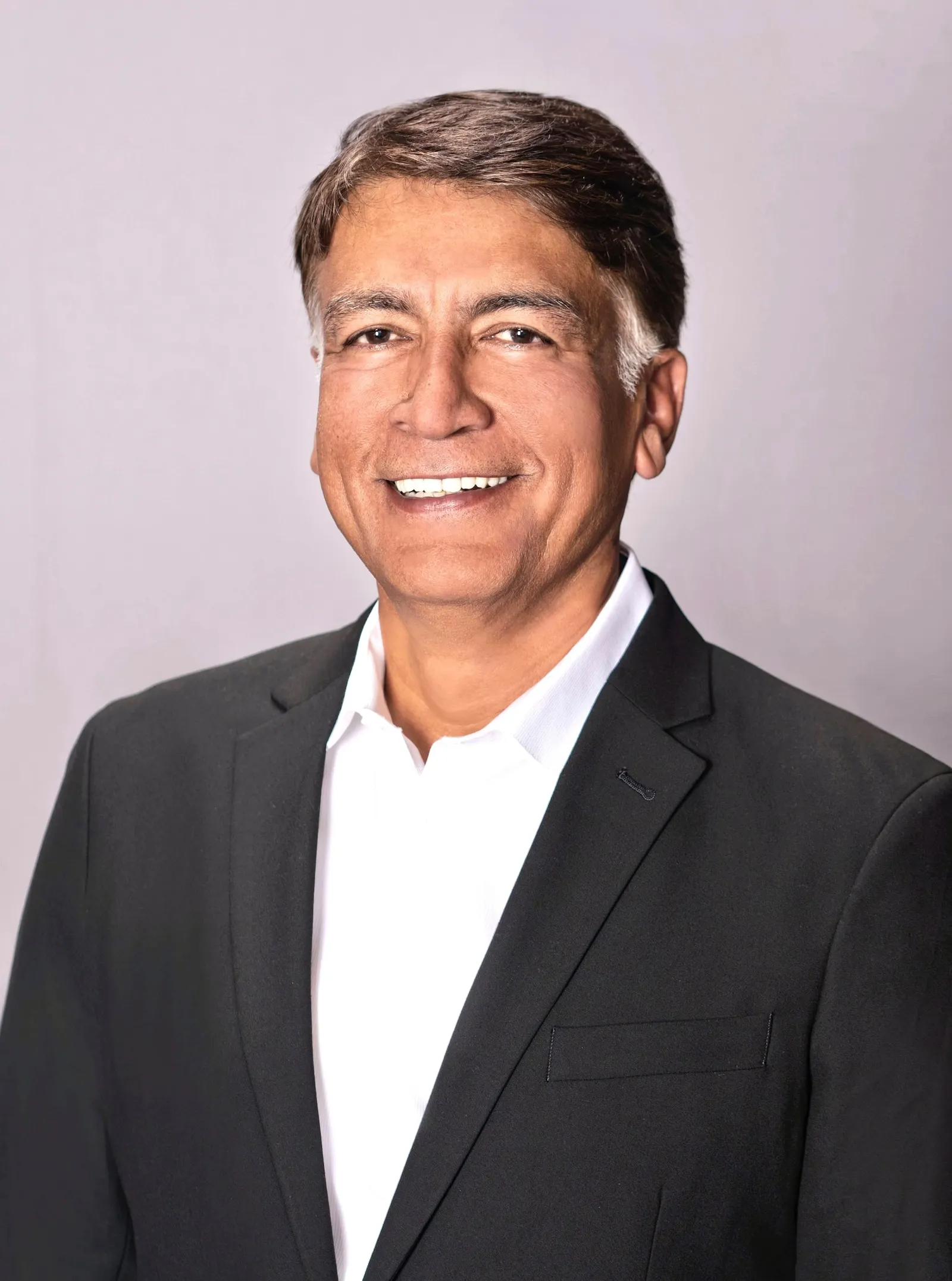 Headshot of man wearing a dark suit and white shirt.