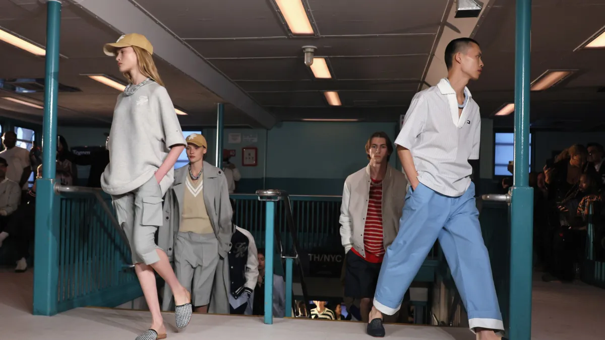 Models walk up subway stairs on both sides wearing clothing from Tommy Hilfiger.