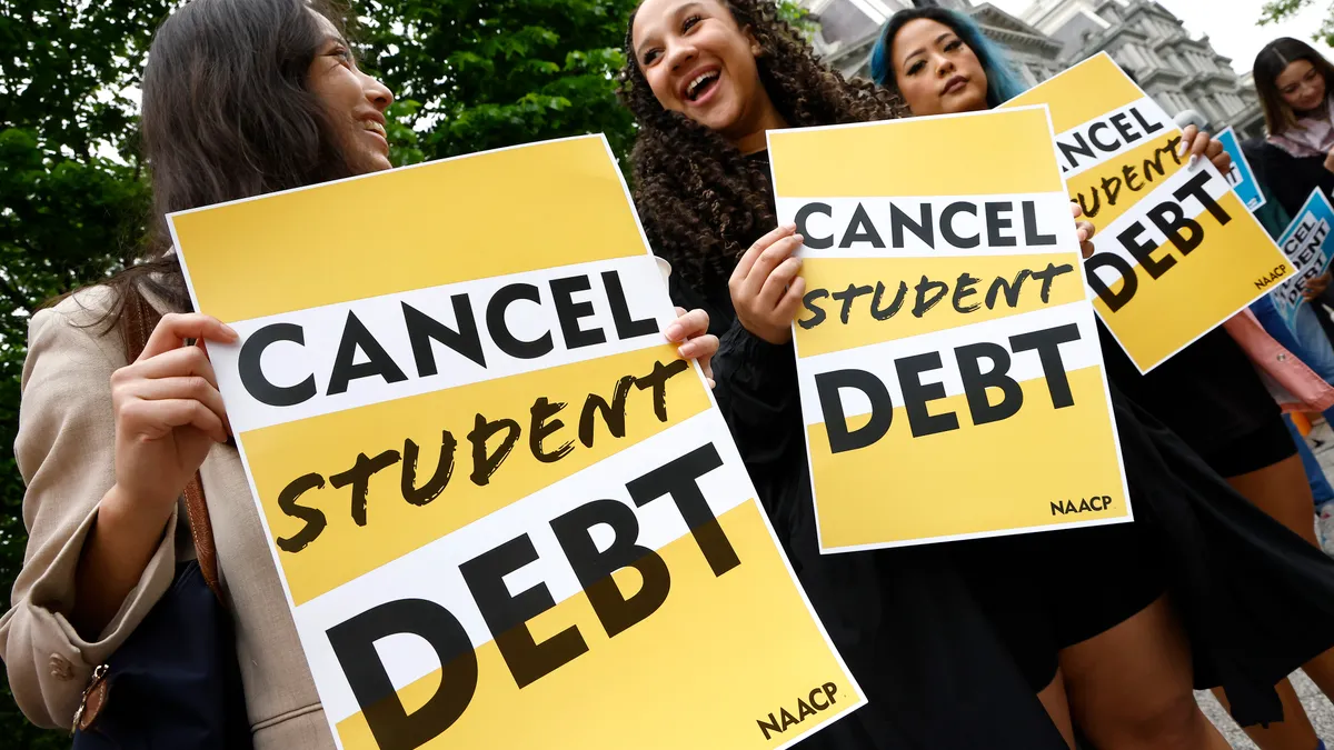 People hold signs saying "cancel student debt."