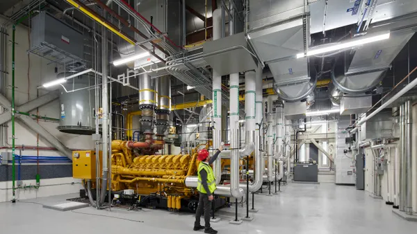 An interior of an industrial setting with pipes and steel-colored machinery.