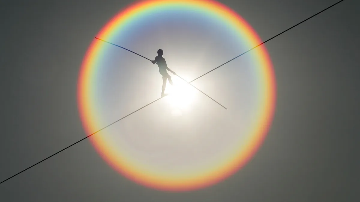 A tightrope walker advances in sunshine.