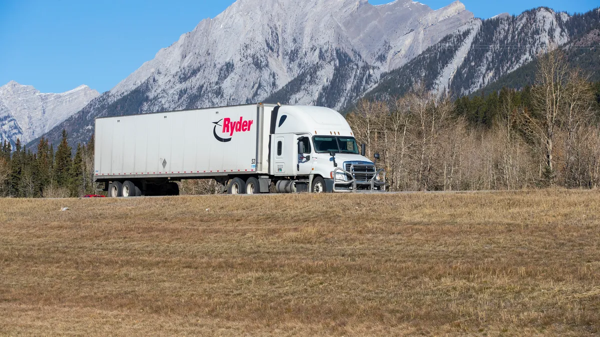 A Ryder tractor-trailer shown with mountains in the background on the Trans-Canada Highway in Canmore, Alberta.